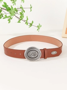 Detailed shot of brown leather belt featuring a vintage silver buckle with radial engravings