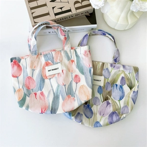 Flat lay view of cute canvas tote bags with pink and purple tulip flower patterns