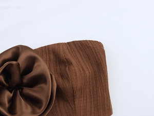 Detail of dark brown tube top featuring a 3D satin flower and pleated texture fabric