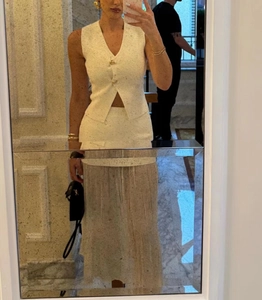Détail du gilet en tricot blanc avec col en V et boutons dorés décoratifs