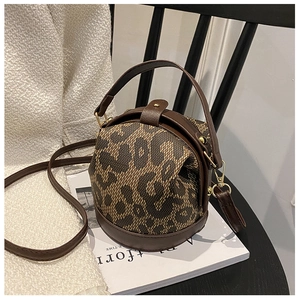 Detail of leopard print spherical handbag with brown PU leather trim on a chair