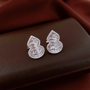 Macro shot of silver gourd earrings with rectangular zircons on dark leather texture