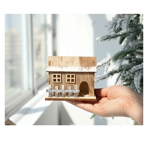 Handheld view of a wooden Christmas house with snow paint and fence details