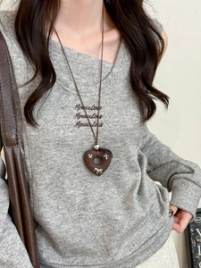Close-up of heart pendant necklace featuring snowflake and horse charms on brown cord