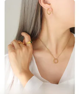 Detail of twisted cable gold jewelry set featuring an oval green gemstone ring on model