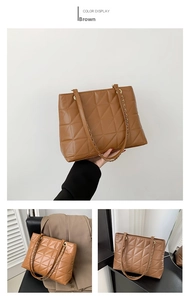 Detail showing the brown quilted leather texture and metal chain strap of the tote bag