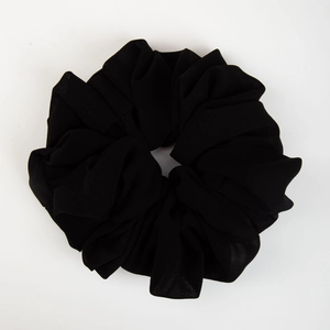 Close-up of a premium black elastic chiffon scrunchie with soft fabric pleats texture
