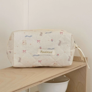 Detailed view of quilted makeup bag with cute bear and rabbit patterns and ribbon puller