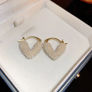 Elegant gold V-shaped heart earrings with white pearls in a premium jewelry box