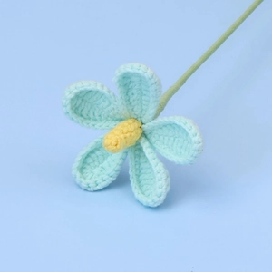 Detailed view of a hand-knitted light blue violet flower with yellow stamen and green stem