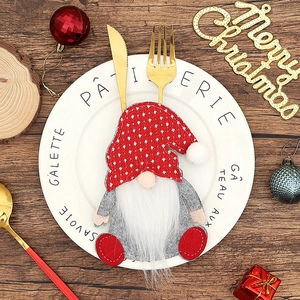 Gnome cutlery holder with red knit hat on white plate with gold silverware for table decor