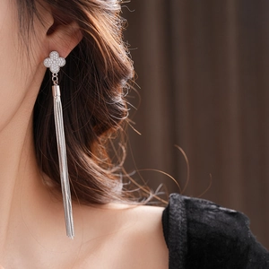 Detail of silver clover earrings with sparkling zircon stones and long flowing tassels