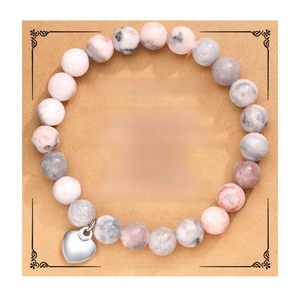 Detail of handmade natural stone bracelet with silver heart charm on best friend card