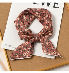 Detail of pink floral cotton scarf knotted on a cork board with magazine background