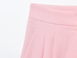 Close-up of pink twill fabric trousers waistline featuring detailed pleat design