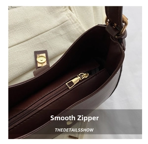 Détail de la fermeture éclair dorée et du fermoir magnétique d'un sac en cuir café