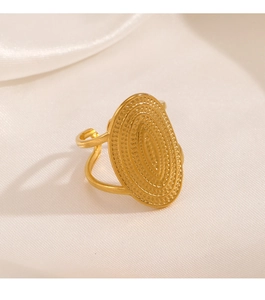 Detailed close-up of an oval gold-plated ring with relief texture on white silk fabric