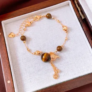 Tiger eye beaded bracelet with golden bell and coin pendant in a wooden jewelry box