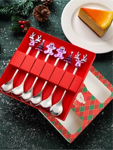 Macro view of six stainless steel Christmas spoons with festive charms in a red gift box