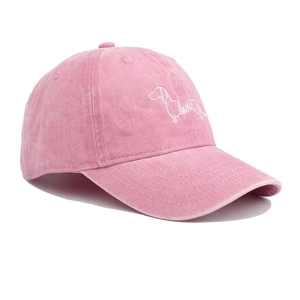 Close-up of pink washed cotton baseball cap with white dog and love letter embroidery