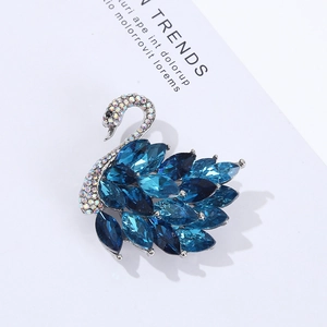 Detailed close-up of crystal swan brooch with blue gradient stones and silver base