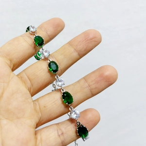 Détail des pierres ovales émeraude et zircon blanc serties sur une chaîne en métal argenté