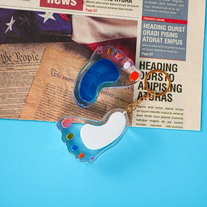 Detail of foot-shaped liquid keychain with blue fluid and glitter on vintage background