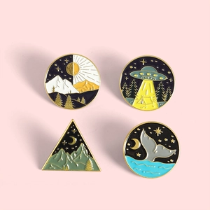 Detail of four enamel pins showing mountain, forest, UFO and whale tail designs