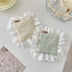 Close-up of square fabric coasters with white lace edges in yellow and green colors