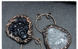 Detail von Buddha-Anhängern aus Obsidian und Frostkristall mit bronzefarbenem Flechtrand