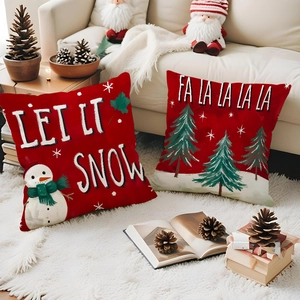 Close-up of red Christmas pillow covers with snowman and tree prints on a cozy sofa