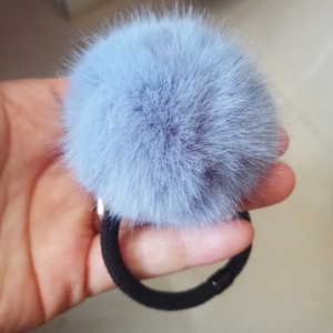 Close-up of fluffy light blue faux fur pom pom hair tie with black elastic band