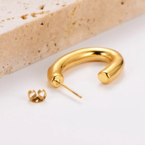 Minimalist gold U-shaped pearl earrings on a natural stone base with a polished finish