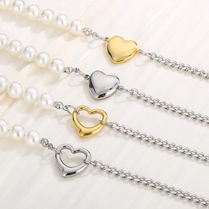 Cuban chain and pearl necklaces with gold and silver heart pendants on soft fabric