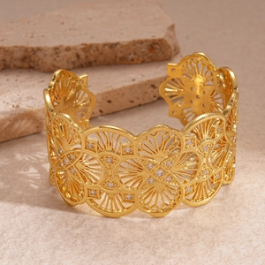 Detail of 18k gold plated open cuff with intricate filigree pattern and zircon studs