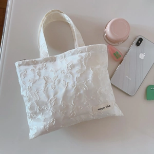 Close-up of white jacquard fabric hand bag with leaf pattern and simple wish label