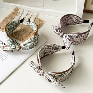 Three paisley print fabric headbands with knot detail in green, pink and beige tones