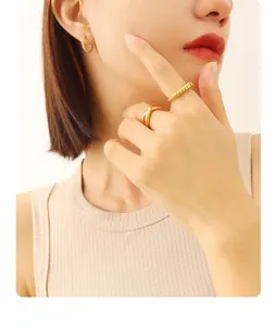 Detail showing 18K gold-plated textured ring and small hoop earrings on model