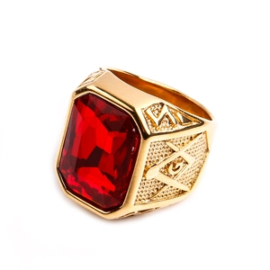 Dettaglio anello massonico dorato con grande pietra rossa e incisione del simbolo G