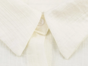 Detailed macro view of shirt pointed collar and button on textured cotton-linen fabric
