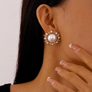 Detail of vintage flower stud earrings featuring pearls and rhinestones on a golden base