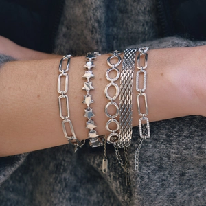 Set of five silver Cuban link bracelets for women with rhinestones on a sweater background
