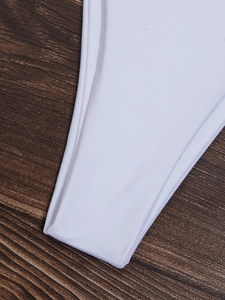 Vista macro del tessuto elastico del bikini bianco con cuciture su legno scuro