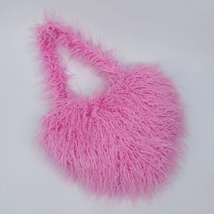 Close-up of fluffy pink heart-shaped handbag made of soft long hair faux fur texture