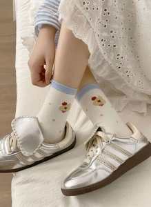 Détail de chaussettes mi-hautes en coton crème avec pois bruns et motif ours mignon