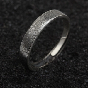Detailed view of brushed dark metal ring featuring a minimalist industrial design texture