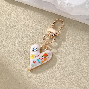 Colorful evil eye heart keychain with floral print and gold metal clasp on stone background
