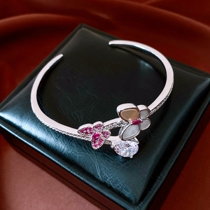 Detailed macro of vintage silver zircon bangle with butterfly shell flower on black leather