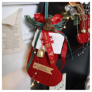 Detail of red knit Christmas stocking with pine cones, golden bells and festive ribbons