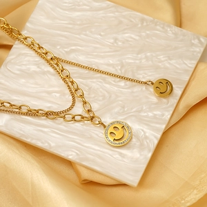 Collier double couche doré avec smiley et strass brillants sur marbre et tissu en soie